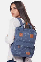 Mochila azul de lona tipo canvas con estampado de flores. Tiene doble asa de mano, correas ajustables para la espalda, cierre superior y bolsillo frontal con cierre.