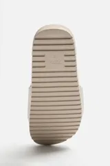 Chancla tipo pala monocolor negra, con suela de goma y tira ancha en el empeine con relieve acanalado.