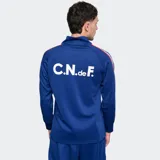 Buzo deportivo de entrenamiento del Club Nacional de Football, color azul, con cuello alto y cierre frontal parcial. Presenta mangas largas con franjas laterales en colores rojo, blanco y azul, y el escudo del club en el pecho.