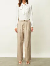 Pantalón de vestir beige de corte recto y tiro alto, con pinzas frontales y trabillas para cinturón.