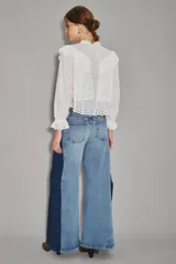 Jean de corte wide leg con diseño bicolor, presentando un panel central en denim lavado claro y paneles laterales en denim azul oscuro. Posee tiro alto y cierre frontal con botón.