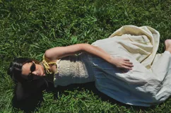 Vestido largo color crema con rayas verticales finas, fruncido en el busto y falda globo. Tiene detalles tejidos de crochet en breteles y escote.