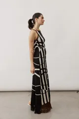 Vestido largo de punto con diseño geométrico y de ondas en color negro y crudo, sin mangas, con escote halter y detalle de flecos en el ruedo.