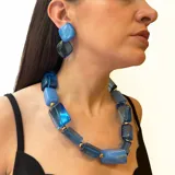Conjunto de collar y aros de resina azul con detalles dorados. El collar es de cuentas grandes rectangulares y los aros son colgantes con forma de rombo.
