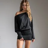 Vestido corto negro de corte holgado en la parte superior con un hombro descubierto y mangas largas, y falda ajustada tipo tubo.