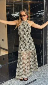 Vestido midi de encaje floral color beige sobre base negra, con cuello halter y falda con vuelo.