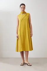 Vestido midi acampanado color mostaza, sin mangas, confeccionado en lino con detalle desflecado en los bordes. Incluye una bufanda del mismo material y color.
