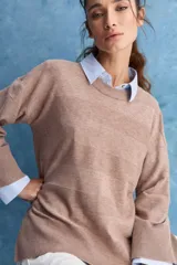Sweater blanco de punto con diseño holgado, cuello redondo, mangas largas acampanadas y detalles de textura horizontal en el tejido.