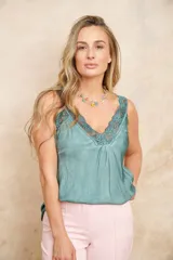 Musculosa de seda color verde con escote en V y detalles de encaje floral en el escote y los tirantes.