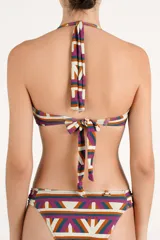 Top de bikini bandeau con estampado geométrico multicolor en tonos terracota, violeta, verde azulado y blanco. Cuenta con tirantes para anudar al cuello y una argolla circular de carey en el centro del busto.