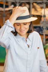 Sombrero de estilo fedora confeccionado en material tejido color tostado, con una franja decorativa negra alrededor de la copa.