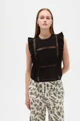 Blusa de algodón negra sin mangas, con cuello a la base, volados en los hombros y detalles de encaje y calados frontales.