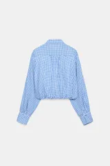 Camisa corta de cuello solapa y manga larga, con estampado de cuadros vichy en color bordó y blanco. Presenta un bolsillo delantero de parche, bajo abullonado con elástico interior y cierre frontal con botones.