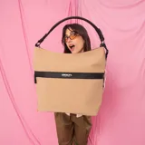Cartera grande color tostado con detalles en negro, confeccionada en tela impermeable. Cuenta con un amplio compartimento principal, bolsillo frontal con cierre oculto, bolsillo trasero con cierre, asa corta de mano y correa larga desmontable.