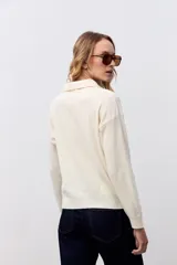 Sweater de punto color crudo, con cuello polo y cierre frontal de tres botones en tono carey. De manga larga y corte holgado.