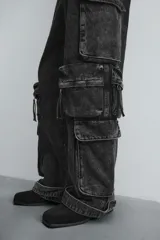 Pantalón cargo de denim lavado negro, corte relajado y tiro medio. Presenta múltiples bolsillos cargo con solapa y detalle de cierre en las perneras, además de bolsillos de vivo traseros. El bajo es ajustable con trabilla.