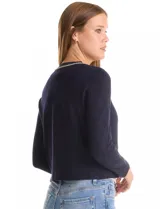 Cardigan corto de punto en color azul marino con textura de rombos en relieve. Presenta un diseño abierto con ribetes decorativos que incluyen detalles de cadena en el cuello, la abertura frontal y los bolsillos simulados.