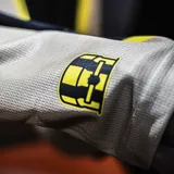 Musculosa de básquet Puma del Peñarol, modelo Third 2025. Diseño en color tostado con dos franjas verticales negras y amarillas en el centro, con el logo de Puma y el escudo del club bordados.