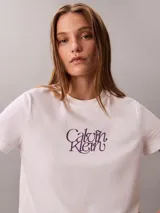 Remera blanca Calvin Klein de manga corta y cuello redondo, con estampado de logo script en el pecho en tono violeta.