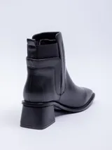 Botas de caña media color marrón, de cuero sintético, con punta cuadrada, taco cuadrado y pieza elastizada en los laterales.