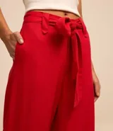 Pantalón de corte pantalona ancho, color rojo vibrante, confeccionado en viscosa y lino. Presenta un lazo de tela para atar en la cintura.