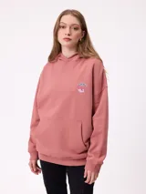 Canguro color rosado con capucha, bolsillo canguro frontal y un pequeño estampado circular en el pecho con un paisaje de montañas y olas.