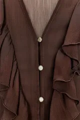 Vestido midi de color marrón con diseño combinado, escote en pico con volantes, mangas largas con puños elásticos y falda evasé. Incluye un cinturón negro con hebilla dorada en la cintura y cierre lateral con cremallera oculta.