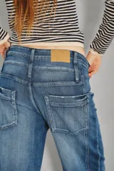 Jean de tiro medio con diseño de doble cintura superpuesta y pierna recta. Confeccionado en denim azul oscuro, presenta cierre y botón metálico, con costuras verticales decorativas en el frente.