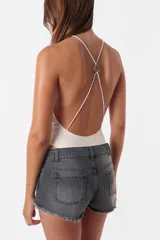 Short de jean gris oscuro, tiro medio, con ruedo desflecado, pasacintos, cierre y botón metálico. Tiene bolsillos delanteros y traseros.