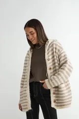 Saco tejido de punto con diseño a rayas horizontales en tonos beige y gris. Presenta capucha con cordones ajustables, cierre frontal con botones de madera, mangas largas y dos bolsillos delanteros.