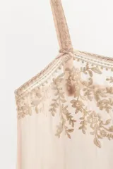 Vestido midi semitransparente de viscosa con escote recto y tirantes finos. Presenta bordados florales a contraste en el pecho y detalle de lazadas ajustables en los laterales.