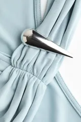 Top halter de punto suave color celeste, con escote asimétrico, tira efecto fular y detalle metálico decorativo con frunces y drapeado lateral.