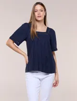 Blusa de corte holgado color azul marino, con escote cuadrado y mangas cortas amplias adornadas con detalles de puntilla calada. Presenta canesú con frunces en el frente.