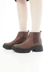 Botas de cuero marrón con suela track negra, diseño estilo Chelsea con inserciones elásticas laterales y cierre lateral.