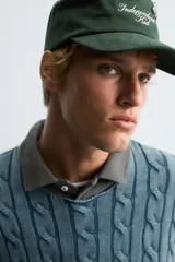 Jersey de algodón de corte relajado, color azul verdoso lavado, con cuello redondo amplio y manga larga. Presenta un tejido de punto con estructura de trenzas verticales.