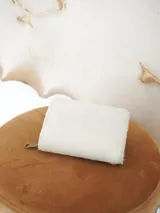 Billetera Actitud Sur de cuero con pelo vacuno en color blanco, con cierre perimetral y compartimentos internos de cuero.