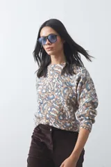 Sweater de punto con diseño de estampado animal print abstracto en tonos tierra y azul claro. Presenta cuello redondo a la base, mangas largas levemente amplias y terminaciones acanaladas en puños y ruedo.