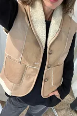 Chaleco de cuero genuino con interior de piel sintética, diseño con cuello solapa, cierre frontal de tres botones y dos bolsillos delanteros aplicados.