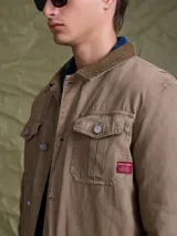 Campera de gabardina color azul marino, con cuello camisero, cierre frontal con botones metálicos y bolsillos frontales con solapa.