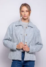 Tapado corto de tweed celeste y blanco, con cuello camisero, cierre frontal con botones veteados y bolsillos grandes.