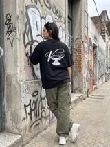 Remera negra de algodón con corte oversize y estampado en la espalda de una paloma blanca y la inscripción "Vinnare - The Brand of the Moment".