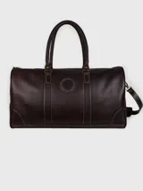 Bolso de viaje tipo duffel de cuero marrón oscuro, con doble asa de mano, correa ajustable para el hombro y detalle de logo grabado en relieve en la parte frontal.