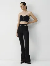 Pantalón negro de lana con elastano, corte ajustado y bota acampanada. Presenta detalle cut out en la cintura, cierre y botón oculto en la parte delantera.