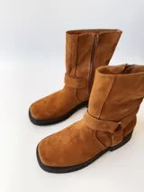 Bota corta de cuero color camel, con correa decorativa alrededor del tobillo y suela de goma negra.