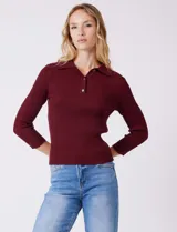 Buzo de tejido acanalado marca Rio & Rian, color beige, con cuello tipo polo con solapa y botones frontales, y mangas tres cuartos.