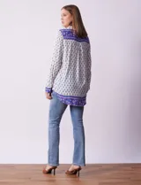 Camisa blanca con estampado floral en azul, de manga larga y cuello con solapa.