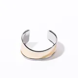 Brazalete rígido dorado con bordes plateados.