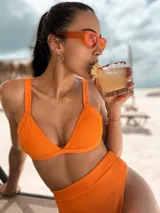 Top de bikini triangular color naranja con textura acanalada, cuenta con breteles regulables y cierre mediante atado en la espalda.
