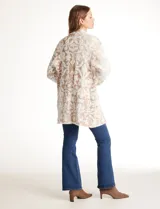 Cardigan abierto de tejido soft, marca Ruby Rd., con patrón de arabescos en relieve en tonos beige y blanco. Tiene cuello solapa fluido, mangas largas de corte recto y bolsillos aplicados en la parte delantera.