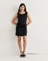 Vestido corto negro sin mangas, con escote redondo y frunces laterales ajustables mediante cordones en la falda.